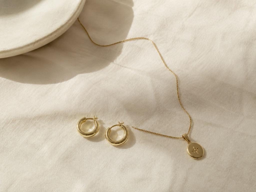 Gold hoops and pendant on linen